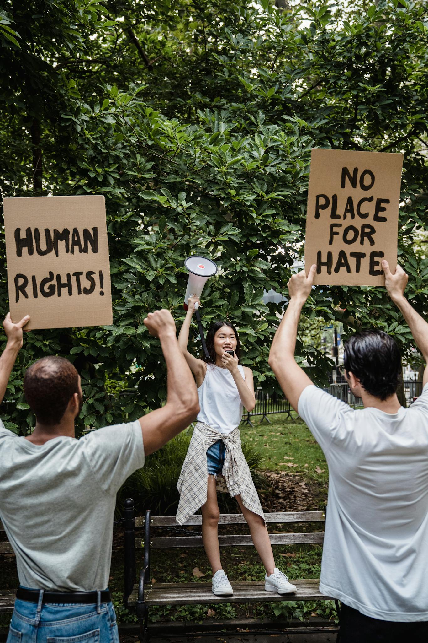A diverse group of activists hold signs promoting human rights and nonviolence at an outdoor protest.