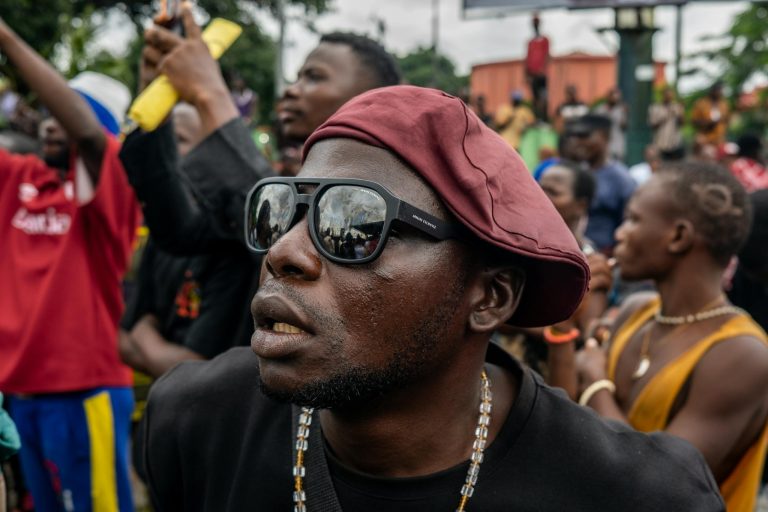 A man at a Nigerian protest wearing a beret and sunglasses, intensely focused.